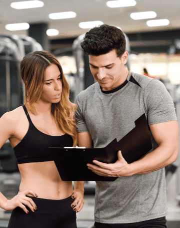 Image of a personal trainer and client looking at a clipboard.