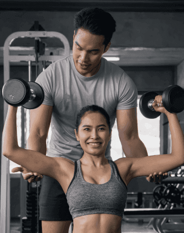 Image of a personal trainer spotting someone while they workout.